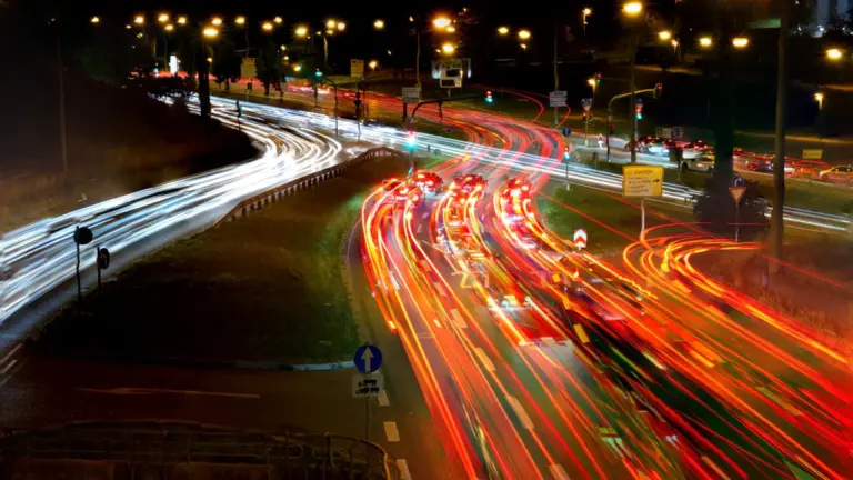 Langzeitbelichtung einer Autobahn bei Nacht mit fließenden Lichtspuren fahrender Autos.