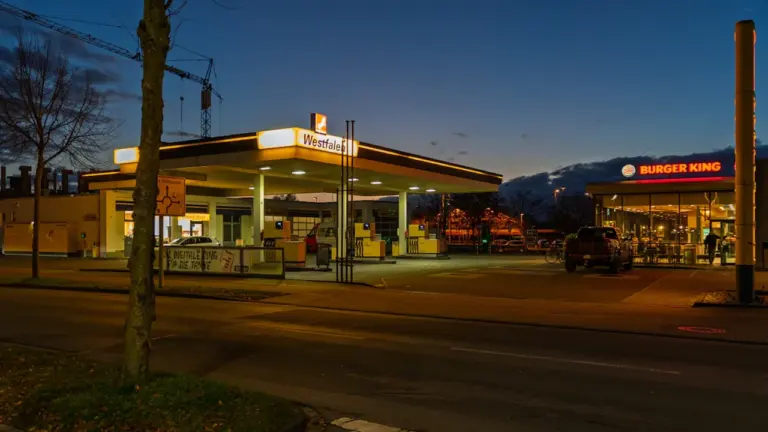Eine beleuchtete Tankstelle mit Burger King Restaurant in den Abendstunden in Coesfeld.