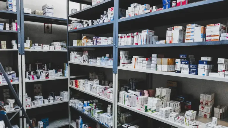 Ein gut gefülltes Arzneimittelregal in einer Apotheke mit zahlreichen Medikamentenschachteln.