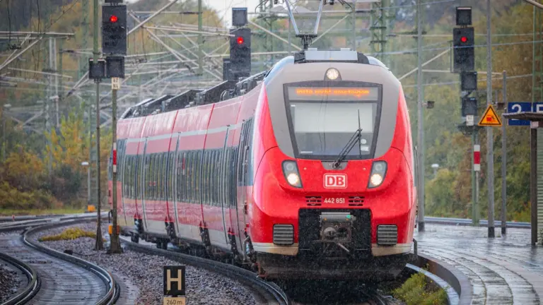 Ein roter Regionalzug der Deutschen Bahn fährt in einen Bahnhof in Deutschland ein.