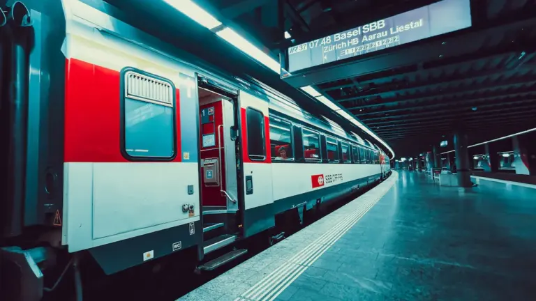 Moderner Zug bei der Einfahrt in einen Schweizer Bahnhof bei Nacht.