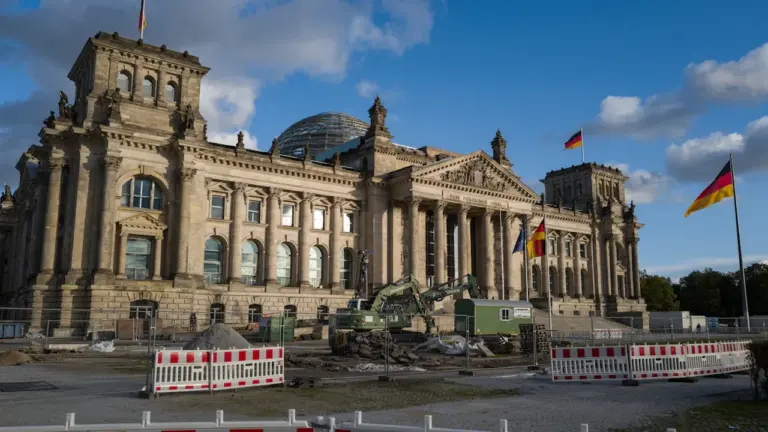 Das Reichstagsgebäude in Berlin bei Tageslicht unter einem blauen, wolkenverhangenen Himmel.