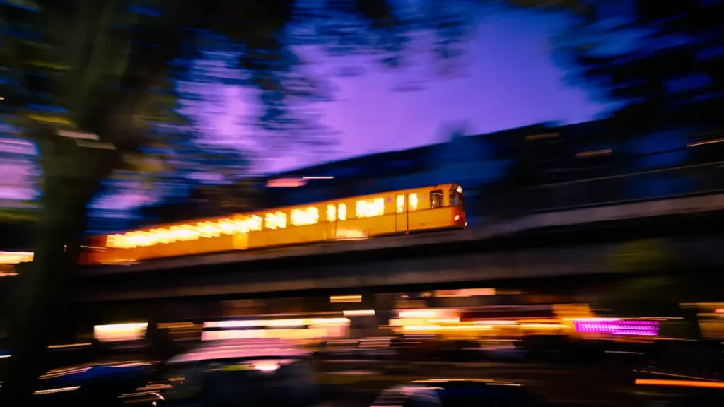 Eine gelbe Berliner U-Bahn fährt bei Dämmerung über eine Hochbahntrasse in Berlin.
