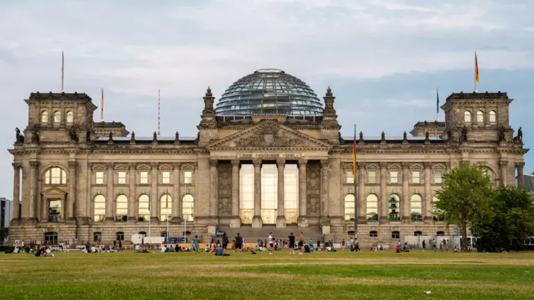 Das Reichstagsgebäude in Berlin bei Tageslicht unter einem blauen, wolkenverhangenen Himmel.