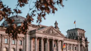Das Reichstagsgebäude in Berlin bei Tageslicht unter einem wolkenlosen blauen Himmel.