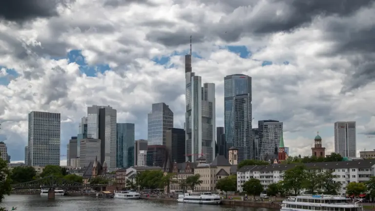 Dunkle, dramatische Gewitterwolken über der Skyline einer deutschen Stadt am Flussufer.