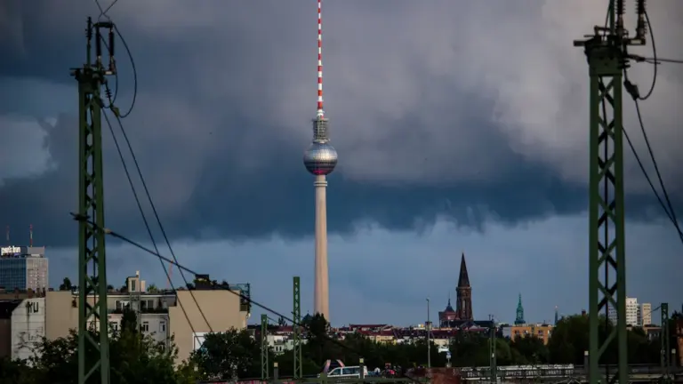 Der Berliner Fernsehturm unter einem dramatischen, wolkenverhangenen und dunklen Himmel.