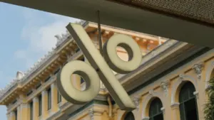 Ein großes Prozentzeichen-Symbol hängt an der Fassade eines klassischen europäischen Bankgebäudes.