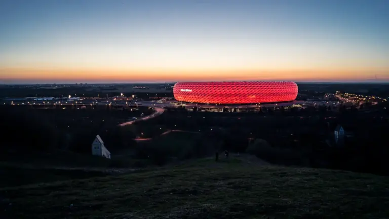 Die von außen rot beleuchtete Allianz Arena bei Nacht in München.