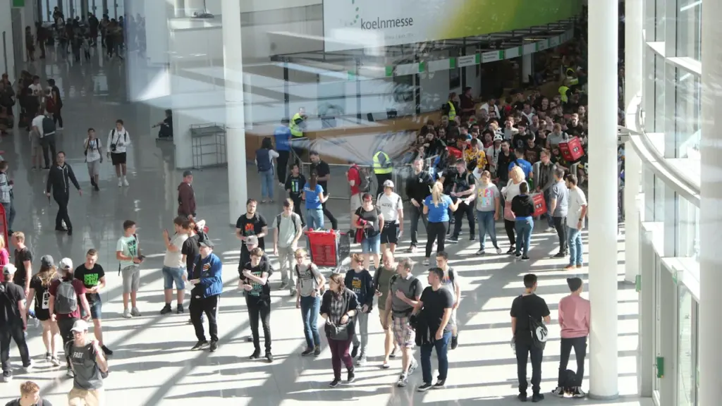 Zahlreiche Besucher betreten das Messegelände der gamescom in Köln bei sonnigem Wetter.