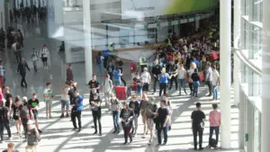 Zahlreiche Besucher betreten das Messegelände der gamescom in Köln bei sonnigem Wetter.