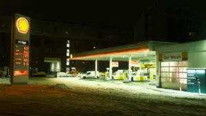Eine beleuchtete Tankstelle bei Nacht mit Schnee auf dem Boden.