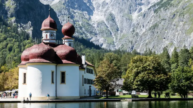 St. Bartholomä Kirche am Königssee vor einer beeindruckenden, steilen Bergkulisse in Bayern.