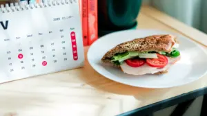 Ein Sandwich auf einem Schreibtisch neben einem Kalender, der den Sonntag symbolisiert.