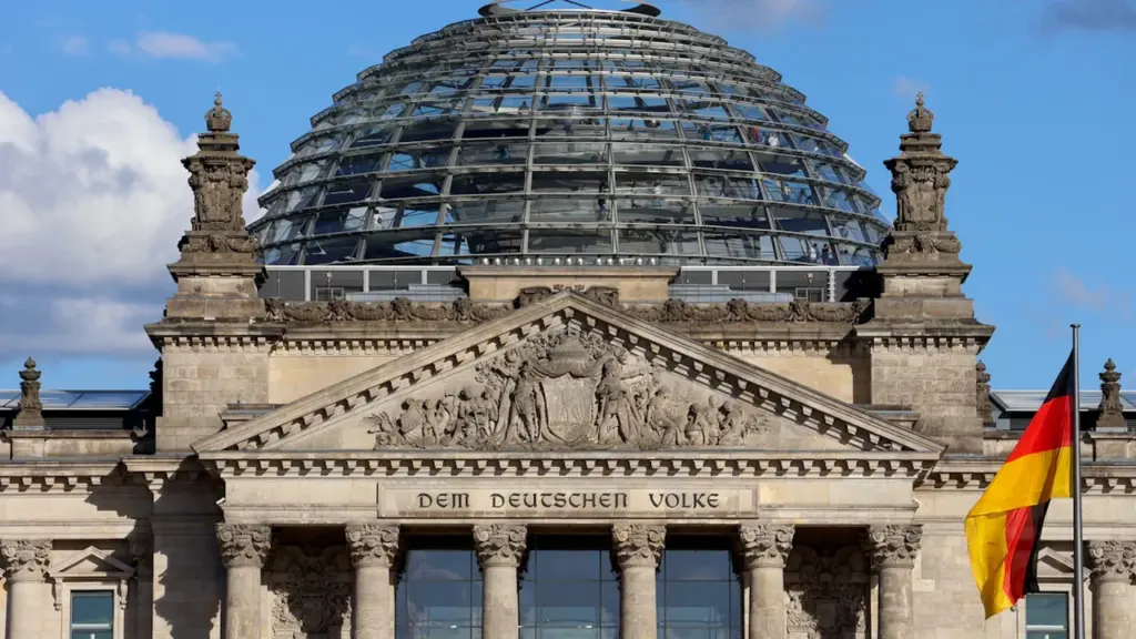 Das Reichstagsgebäude in Berlin mit Glaskuppel und wehender deutscher Flagge.
