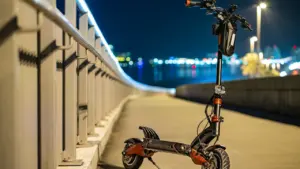 Ein elektrischer E-Scooter steht nachts auf einem beleuchteten Weg im Freien.