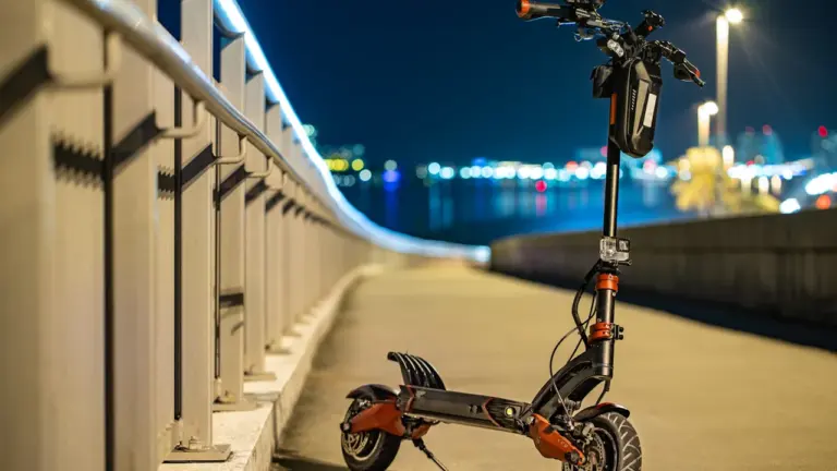 Ein elektrischer E-Scooter steht nachts auf einem beleuchteten Weg im Freien.
