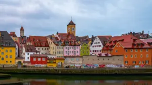 Blick auf die historische Regensburger Altstadt mit bunten Fassaden am Flussufer bei Tag.