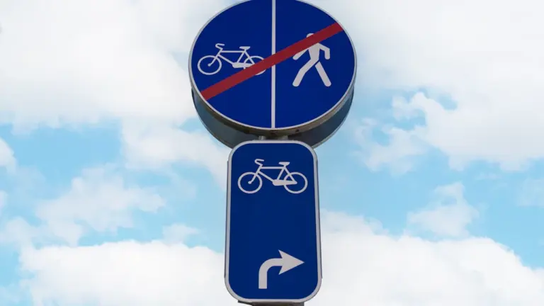 Blaues Verkehrsschild für Radfahrer vor einem hellen, bewölkten Himmel in Deutschland.