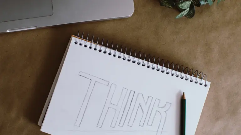 Ein weißer Spiralblock mit dem Wort Think auf einem Schreibtisch mit Stift.