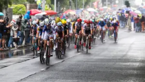 Radrennfahrer im dichten Peloton bei Regenwetter auf einer Straße in Deutschland.