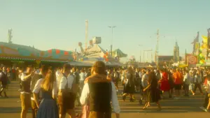 Besucher in traditioneller bayerischer Kleidung auf dem Gelände des Münchener Oktoberfestes bei Sonnenschein.