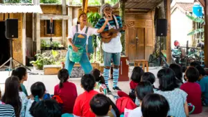 Zwei Entertainer unterhalten eine Gruppe von Kindern mit Musik bei einer Veranstaltung.