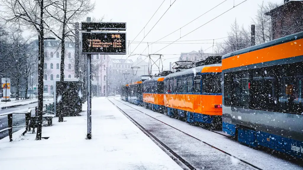 Eine Straßenbahn an einer Haltestelle in Leipzig während eines starken Schneefalls.