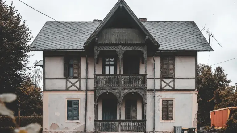 Ein altes, leerstehendes zweistöckiges Haus mit nostalgischer Architektur in einer ländlichen Umgebung.