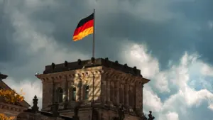 Die deutsche Flagge weht stolz vor einem historischen Gebäude bei bewölktem Himmel.