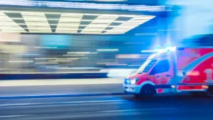 Ein Rettungswagen bei nächtlicher Einsatzfahrt mit Blaulicht in deutscher Stadt.